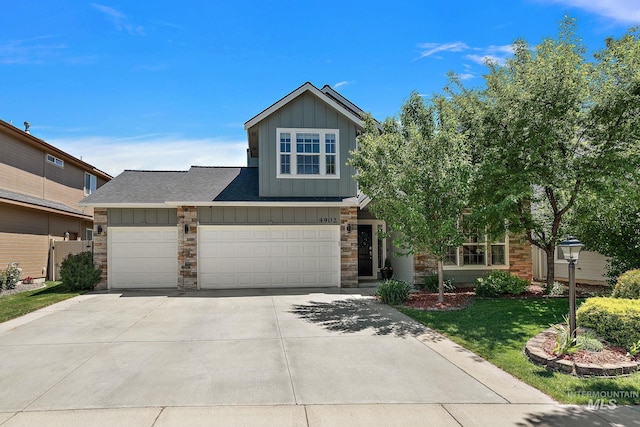 4902 N Schubert Ave, Meridian, ID 83646 - view of front of house featuring board and batten siding, driveway, stone siding, a front lawn, and an attached garage