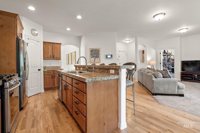 4902 N Schubert Ave, Meridian, ID 83646 - kitchen with arched walkways, a sink, a breakfast bar area, appliances with stainless steel finishes, and open floor plan