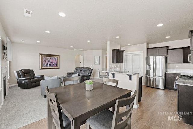 dining space featuring visible vents, baseboards, a fireplace, recessed lighting, and light wood-style floors