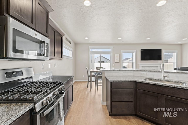 kitchen with a sink, dark brown cabinetry, appliances with stainless steel finishes, and light wood-style flooring
