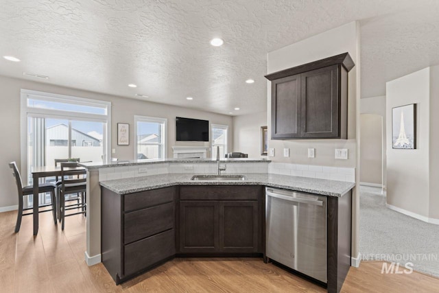 kitchen with a sink, stainless steel dishwasher, a peninsula, and dark brown cabinetry