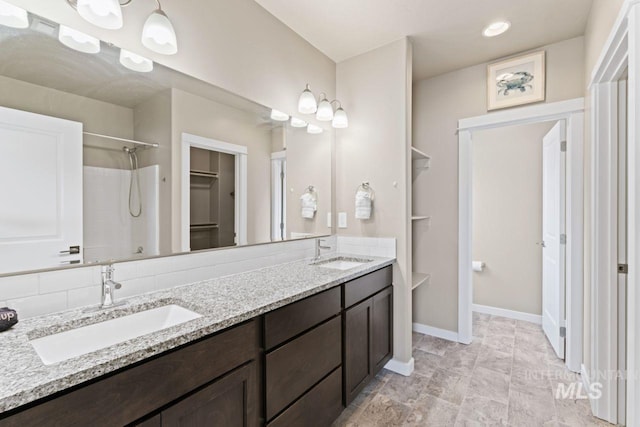 full bathroom with a sink, baseboards, walk in shower, and double vanity