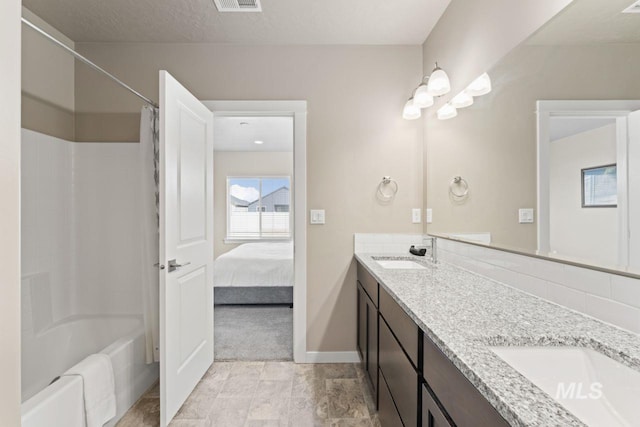 ensuite bathroom with a sink, baseboards, shower / bath combo, and double vanity