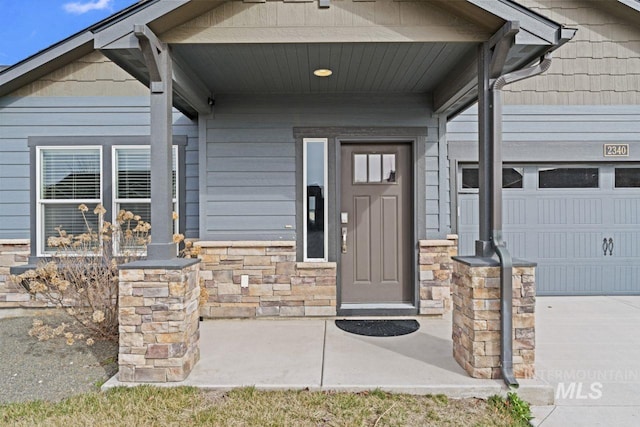 entrance to property featuring stone siding, driveway, a porch, and an attached garage