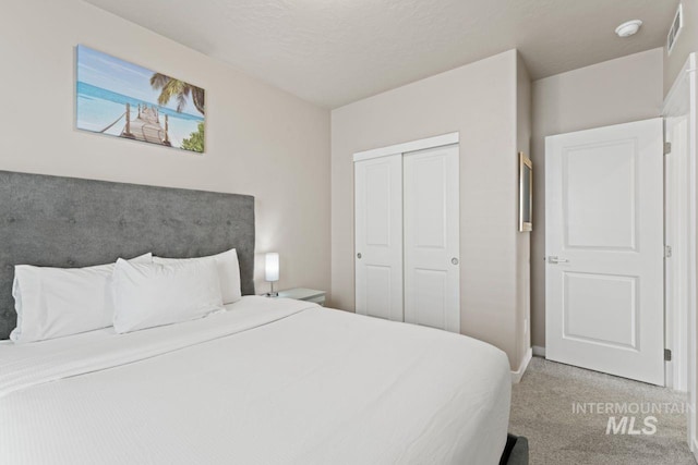 carpeted bedroom featuring baseboards, visible vents, and a closet