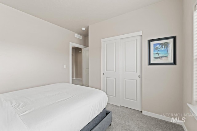 bedroom featuring light colored carpet, visible vents, a closet, and baseboards