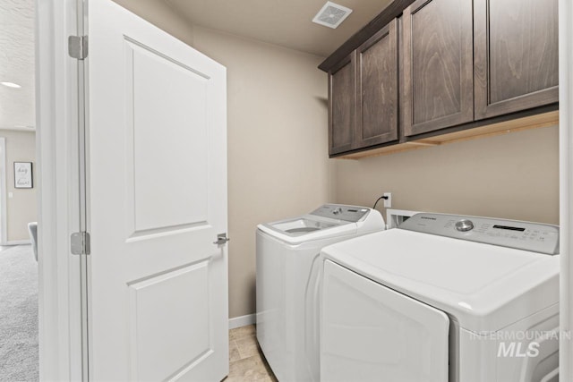 laundry area featuring visible vents, light carpet, washer and clothes dryer, cabinet space, and baseboards