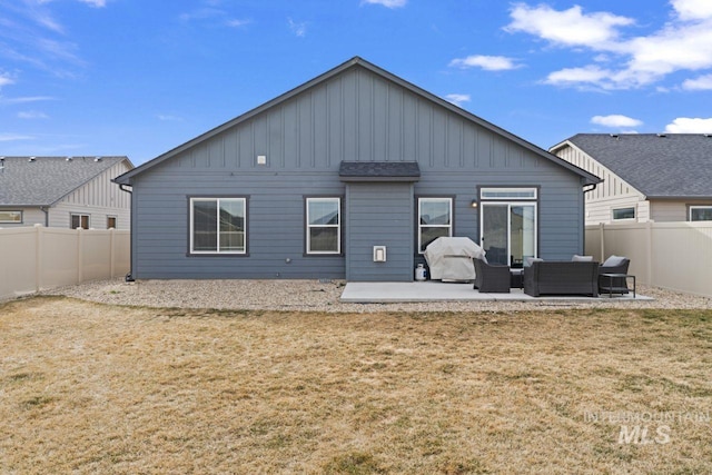 back of house with an outdoor living space, a fenced backyard, a yard, board and batten siding, and a patio area