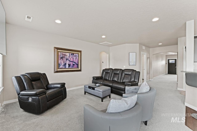 living area with visible vents, baseboards, light carpet, recessed lighting, and arched walkways