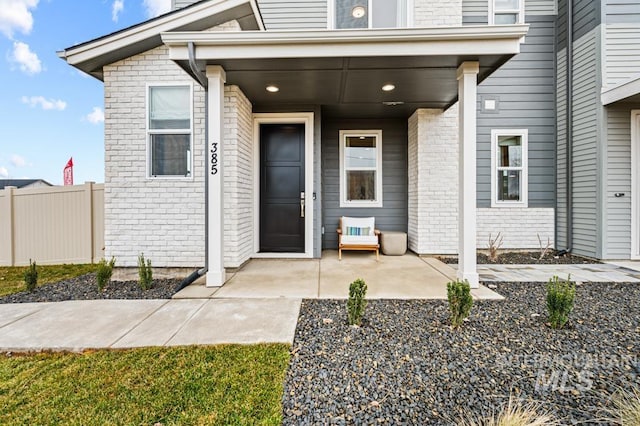 property entrance with brick siding, a patio area, and fence