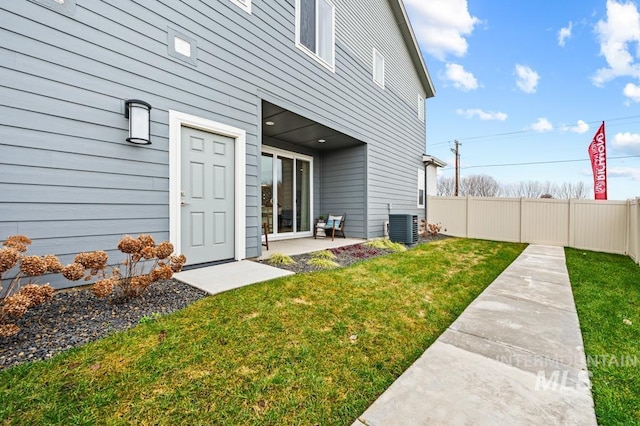 property entrance featuring a yard, a patio area, central AC unit, and fence