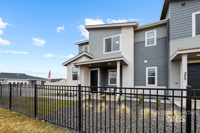 view of front of property with brick siding, a fenced backyard, and a front yard