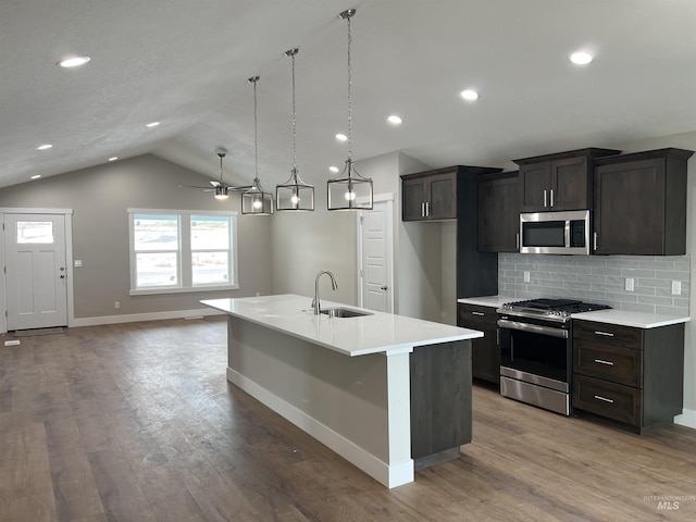 kitchen featuring pendant lighting, sink, stainless steel appliances, a center island with sink, and vaulted ceiling