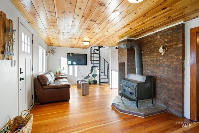 living room featuring a wood stove, light hardwood / wood-style flooring, and wood ceiling