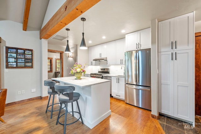 kitchen featuring light stone counters, stainless steel appliances, a kitchen island, pendant lighting, and white cabinetry