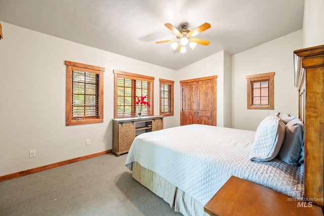 carpeted bedroom with ceiling fan, lofted ceiling, and a closet