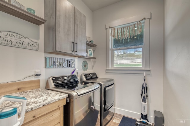 laundry room with cabinet space, baseboards, washing machine and dryer, and light wood-style flooring