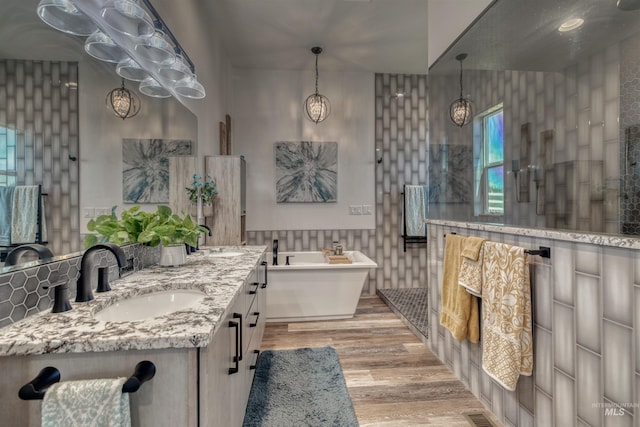bathroom with double vanity, a sink, a freestanding tub, and wood finished floors