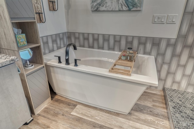 bathroom featuring wood finished floors and a bath