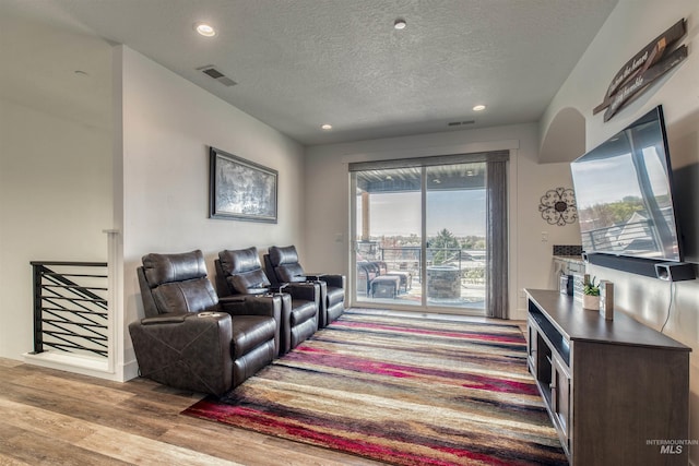 living area with recessed lighting, a textured ceiling, visible vents, and wood finished floors