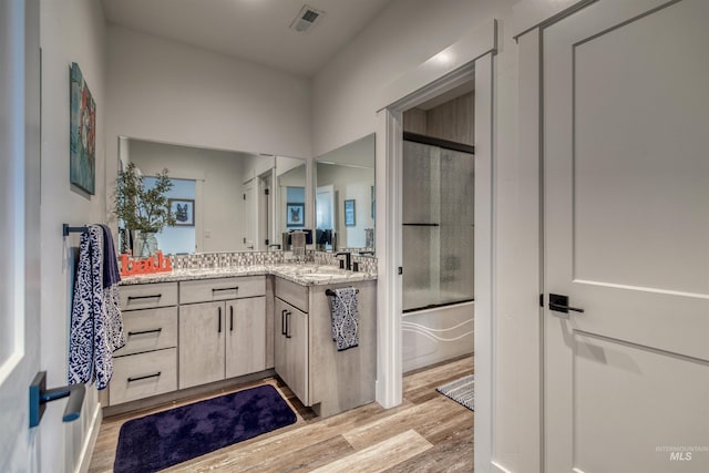 full bath featuring enclosed tub / shower combo, visible vents, wood finished floors, and vanity