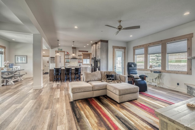 living room with baseboards, ceiling fan, recessed lighting, and light wood-style flooring