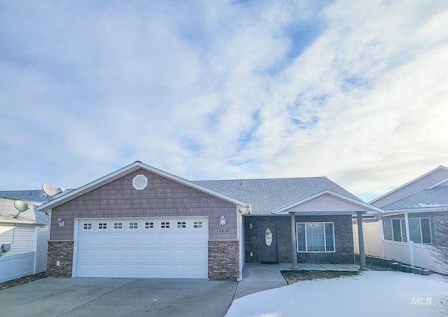 view of front of house featuring roof with shingles, fence, a garage, stone siding, and driveway