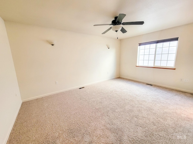 carpeted empty room featuring ceiling fan, visible vents, and baseboards