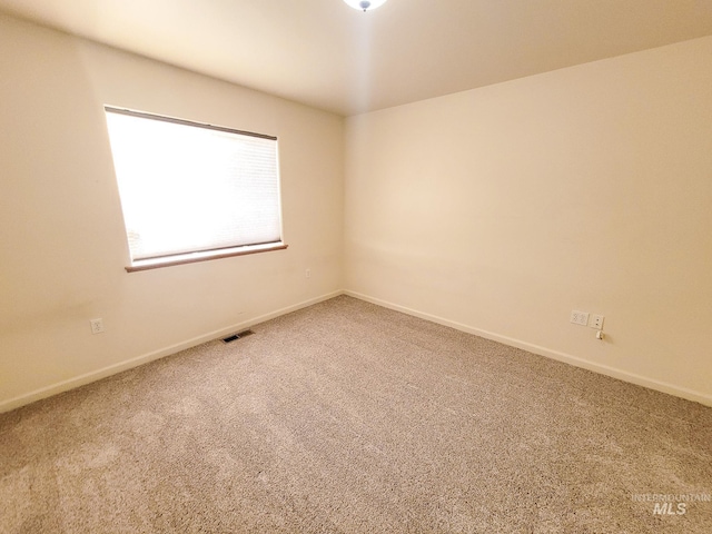 carpeted empty room featuring baseboards and visible vents