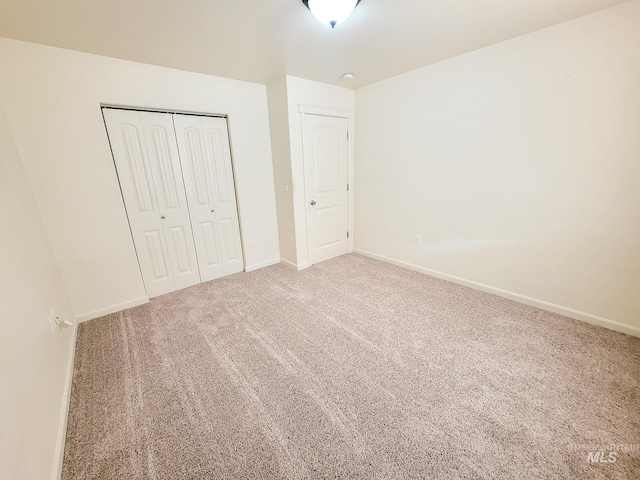 unfurnished bedroom with carpet floors, baseboards, and a closet