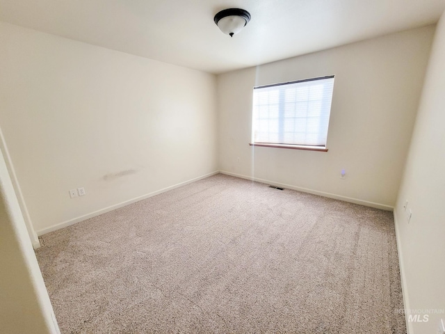 carpeted spare room with visible vents and baseboards