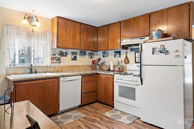 kitchen featuring sink, tasteful backsplash, a notable chandelier, wood-type flooring, and white appliances