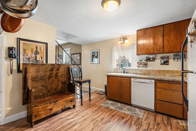 kitchen featuring white dishwasher, light hardwood / wood-style floors, sink, and a textured ceiling