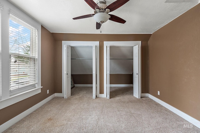 unfurnished bedroom with lofted ceiling, multiple windows, multiple closets, and ceiling fan