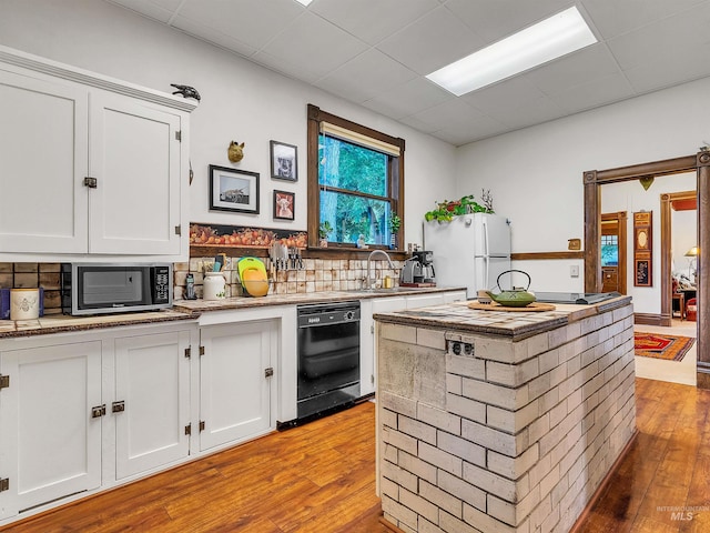 1408 N 7th St, Boise, ID 83702 - kitchen with black dishwasher, a sink, stainless steel microwave, light wood finished floors, and white cabinetry