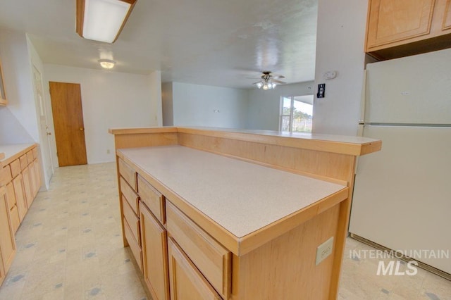 kitchen featuring a center island, ceiling fan, white refrigerator, and light brown cabinets