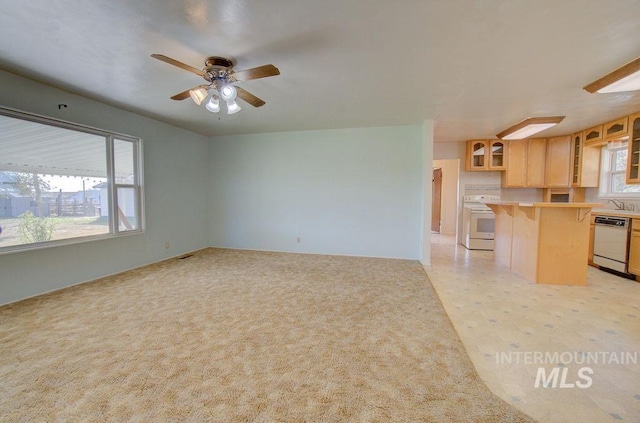 unfurnished living room with ceiling fan, sink, and light carpet