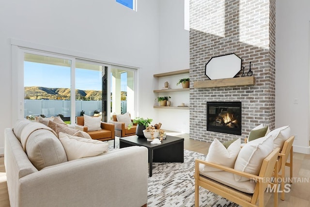14241 N Woodpecker Ave, Boise, ID 83714 - living room featuring wood finished floors, a fireplace, a towering ceiling, baseboards, and a mountain view