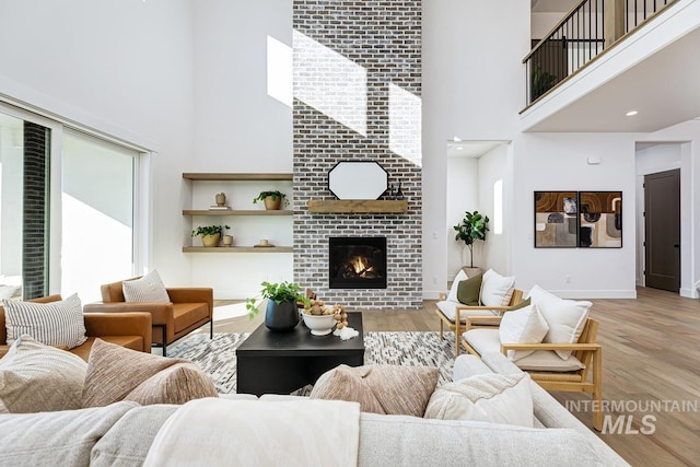 14241 N Woodpecker Ave, Boise, ID 83714 - living room featuring a high ceiling, light wood-style flooring, a fireplace, and baseboards