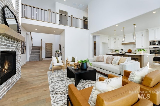 14241 N Woodpecker Ave, Boise, ID 83714 - living area featuring light wood-type flooring, stairway, a fireplace, a towering ceiling, and recessed lighting