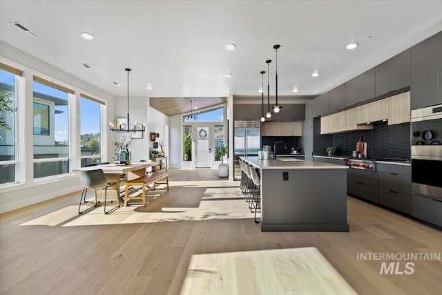 3501 E Planet Dr, Boise, ID 83712 - kitchen featuring modern cabinets, a sink, a center island with sink, decorative backsplash, and recessed lighting
