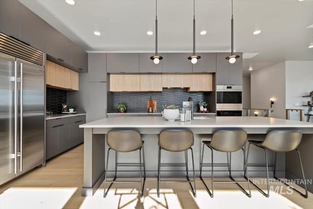 3501 E Planet Dr, Boise, ID 83712 - kitchen with appliances with stainless steel finishes, modern cabinets, decorative backsplash, a sink, and a breakfast bar area