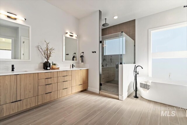 3501 E Planet Dr, Boise, ID 83712 - bathroom with a stall shower, double vanity, a soaking tub, baseboards, and wood finished floors