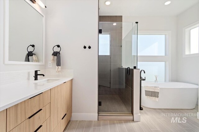 3501 E Planet Dr, Boise, ID 83712 - bathroom featuring vanity, a stall shower, a freestanding tub, recessed lighting, and baseboards