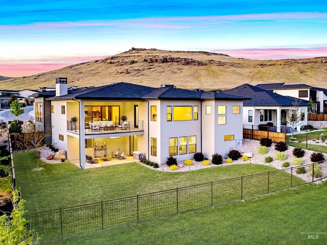 3501 E Planet Dr, Boise, ID 83712 - back of house at dusk with stucco siding, a patio, a chimney, a balcony, and a mountain view