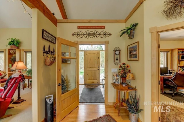 entryway with plenty of natural light, crown molding, and light wood-type flooring