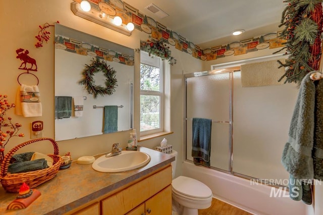 full bathroom with toilet, shower / bath combination with glass door, hardwood / wood-style floors, and oversized vanity