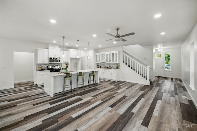 kitchen with backsplash, an island with sink, appliances with stainless steel finishes, white cabinetry, and a sink