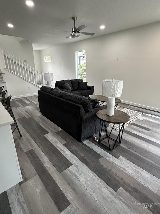 living area with stairway, a ceiling fan, wood finished floors, baseboards, and recessed lighting