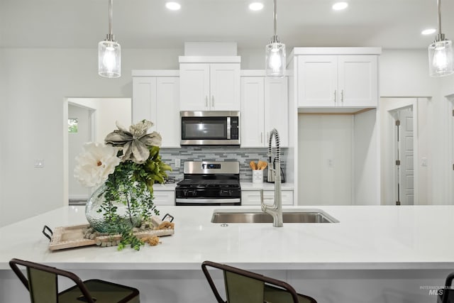 kitchen with backsplash, light countertops, a kitchen breakfast bar, stainless steel appliances, and a sink